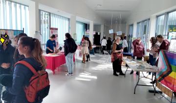 salle avec plusieurs stands d'information et des personnes qui discutent